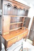 A Georgian oak dresser having plate rack with two cupboards and trinket drawers over open base