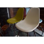 A pair of modern designer chairs, by Vitra after Eames, having dark maple legs, in mustard & cream -