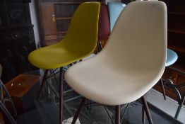 A pair of modern designer chairs, by Vitra after Eames, having dark maple legs, in mustard & cream -