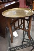 A Middle Eastern/North African style brass tray table on folding bamboo frame, having geometric