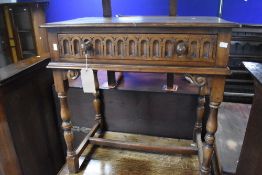 A reproduction oak side table in the Priory style having frieze drawer, turned frame and H