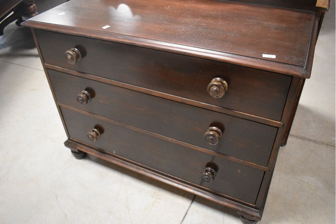 A Victorian dark stained pine chest of three long drawers, having shaped ledge back and turned - Image 1 of 4