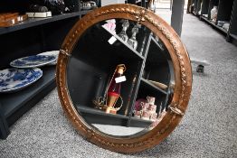 A 20th-century Arts and Crafts-style copper mirror of circular form, featuring a hammered copper,