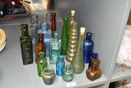 A selection of late 19th to early 20th-century coloured glass bottles, to feature blue, amber, green