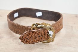 A vintage brown and orange snakeskin textured belt, having a brass scrolled buckle, most likely a