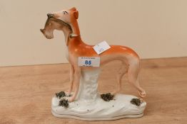 A Victorian Staffordshire Pottery hunting dog figure, to feature a slender greyhound holding a small
