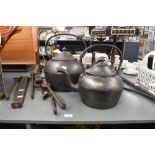 Two large Victorian cast iron kettles, featuring a prominent finial, domed lid and curved spout;
