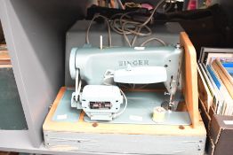 A vintage Singer electric table-top sewing machine, having a metal body upon a wooden base, in the