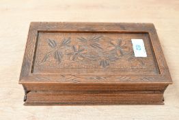 A vintage carved wood cigarette dispenser box, in the shape of a book, featuring floral detailing,