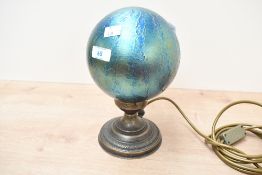 A 20th-century Heron Glass table lamp, having an iridescent teal blue orb shade upon a gilt metal