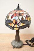 A small contemporary Tiffany-style dragonfly table lamp, featuring a leaded orange shade with
