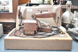 A mid 20th-century Singer Sewing machine, featuring a chocolate brown metal body and electric motor,