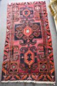 A vintage Persian Navahand rug, having a burgundy ground with bright red and black geometric design,