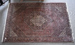 A hand knotted wool Persian Bidjar area rug, having a red brown ground with cream and blue