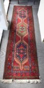 A 20th century vintage hand knotted runner rug in 100% Pure New Wool, has a rich red ground