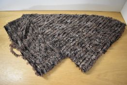 A length of textured brown fabric with taupe and cream silky fibres woven using a tasselled and