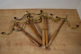 Six rotating gown and wig hangers, with brass hooks and wood handles.