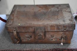 A large antique suitcase in brown leather, has tooled details, handles, buckles w brass hardware,