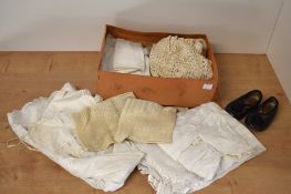 A box of mid 20th century white cotton and beige knitted babies or children's clothes, along with