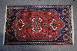 A Persian Qashqai hand knotted wool small area rug, with birds and floral central design on a red