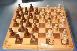 A vintage handmade wooden chess set, featuring novelty pyrography pieces, which can be stored inside