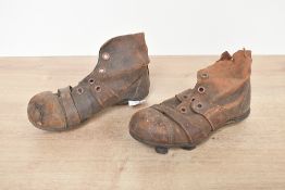 A small pair of early 20th-century brown leather child's football boots, featuring high ankles,