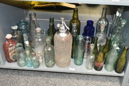 A selection of mixed antique and vintage glass bottles, including wire-bound soda siphon, coloured