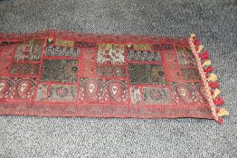 A small vintage Turkish-style runner rug, featuring red and gilt stitching of traditional motifs,