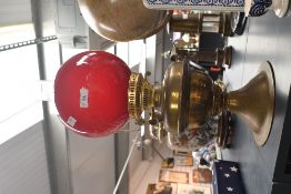 A Victorian brass and glass oil lamp, having ruby red glass globe shade, a clear glass chimney and