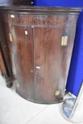 A 19th Century Georgian style bow fronted corner cupboard having line inlay swag decoration,