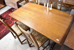 A vintage oak dining suite, by Wood Bros, comprising refectory style table and four chairs, the