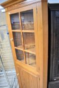 A vintage pine corner display cabinet with cupboard to base
