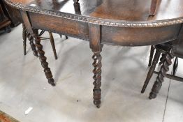 An early 20th Century oak wind out closing dining table having circle/oval top and twist legs,