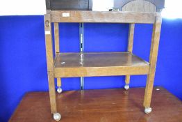 An Arts & Crafts golden oak tea trolley by 'Acornman' (Alan Grainger) , the top section being carved
