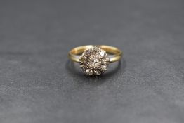 A yellow metal diamond daisy cluster ring stamped 18ct having a central diamond within a surround of