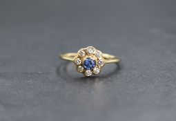A 9ct gold sapphire and diamond set daisy cluster ring, the central bezel set sapphire in an eight