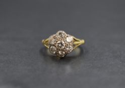 An 18ct gold diamond set daisy cluster ring, the central round brilliant cut diamond measuring