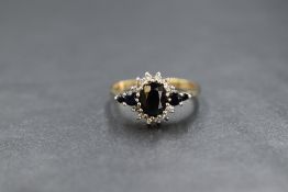A 9ct gold sapphire and diamond set cluster ring, the central oval cut sapphire in a diamond chip