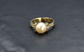 A yellow metal presumed gold pearl and diamond set ring, the central cultured pearl having a cream