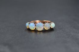 A yellow metal 5 stone opal ring having five graduated matched round opals in claw set mounts on a