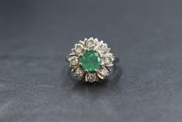 An 18ct white gold emerald and diamond cluster ring, the central claw set emerald being approx 1ct