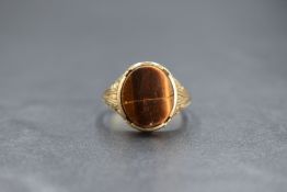 A 9ct gold tiger's-eye set signet ring, in a bezel setting with decorative scroll gallery and