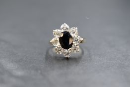 A 9ct gold sapphire and cubic zirconia set cluster ring, the central oval cut sapphire measuring
