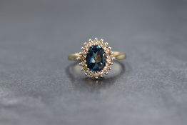 A 9ct gold oval blue topaz and diamond chip cluster ring having a 1ct blue toapz stone surrounded by