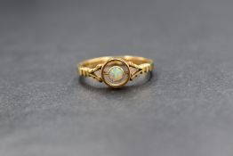 A yellow metal opal ring, the small opal cabochon of good colour in a bezel mount within an outer