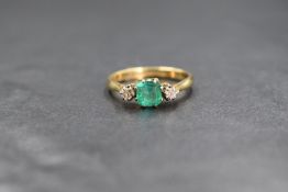 An 18ct gold emerald & diamond ring having a central square baguette cut emerald flanked by two claw