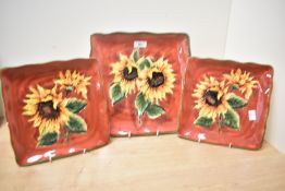 Three late 20th-century ceramic hand-painted sunflower decorated serving dishes, of square form,