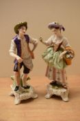 A pair of German porcelain figures depicted as a gentleman resting on a spade and a female holding a