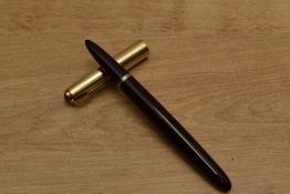 A Parker 51 aerometric fill fountain pen in Dark Burgundy with Rolled Gold converging lines cap.