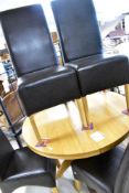A modern golden oak dining table , having circular top on 'rocket' column, and a set of four similar